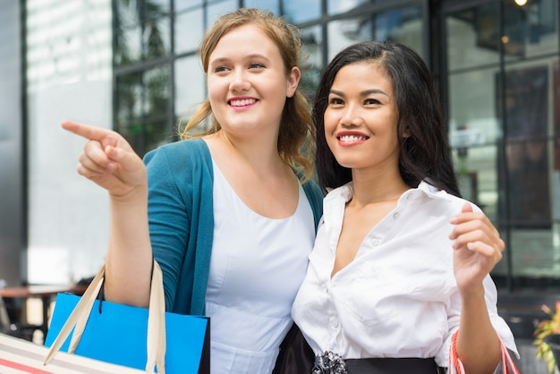 Due donne felici che camminano e che acquistano all&#39;aperto