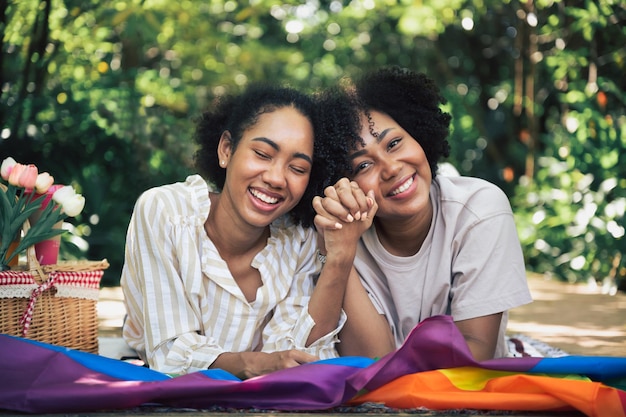 Due donne felici si sdraiano con la bandiera LGBT in giardino