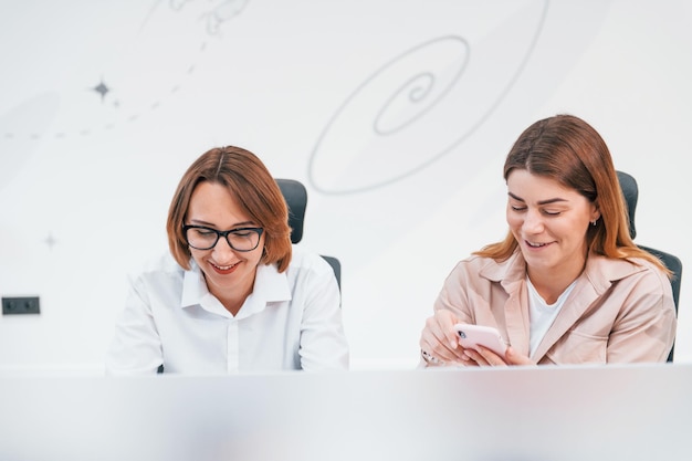 Due donne in abiti formali sedute al tavolo e al lavoro