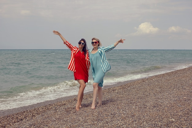 Due donne in giacca e cravatta a righe sono in piedi sulla spiaggia