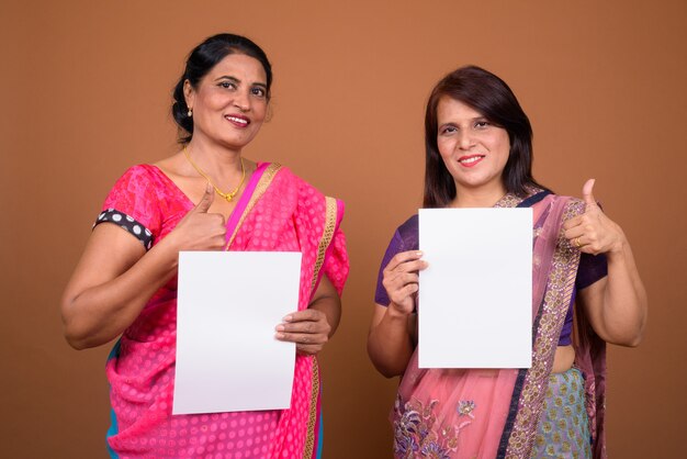 due donne indiane mature che indossano abiti tradizionali indiani Sari insieme a carta bianca