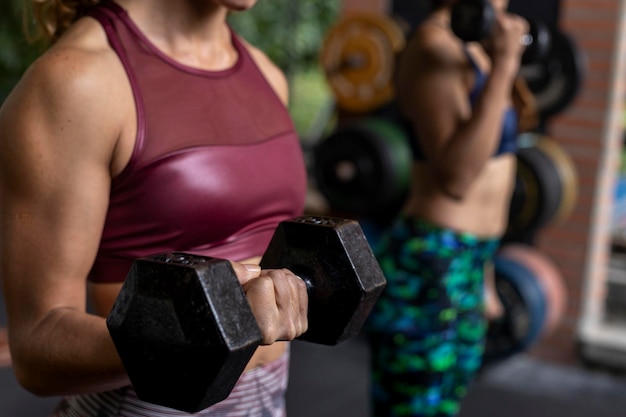 Due donne latinoamericane irriconoscibili eseguono allenamenti funzionali ad alta intensità in palestra usando manubri Concetto di stile di vita sano