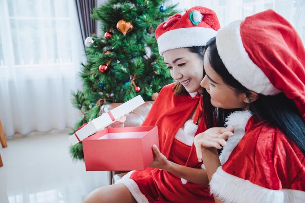 Due donne sexy di Santa aprono scatole regalo insieme a un sorriso felice a casa nel festival di Natale.