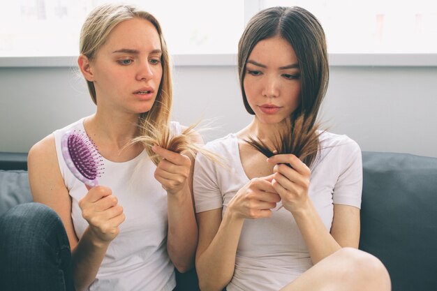 Due donne siedono a casa e discutono dei problemi con i capelli