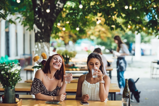 Due donne sorridenti felici che bevono acqua nella caffetteria