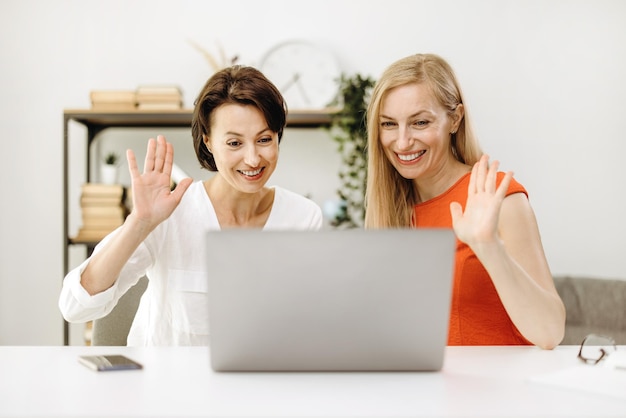 Due donne sorridenti mature hanno una conferenza di videochat utilizzando il laptop