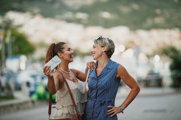 Due donne sorridenti si divertono e si divertono in una giornata estiva mentre camminano lungo le strade di una città mediterranea.