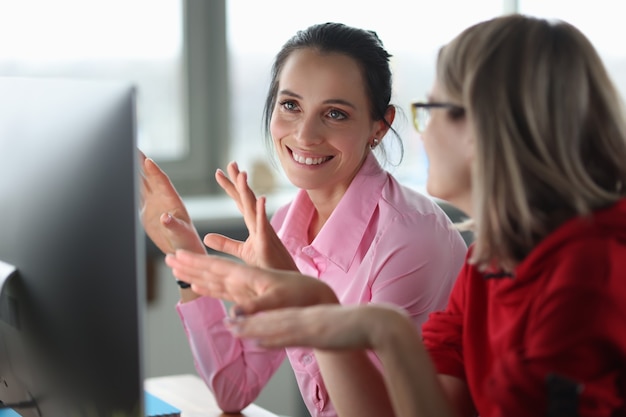 Due donne sorridenti sono sedute al concetto di corsi didattici per computer