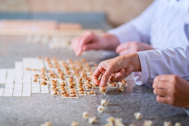 Due donne stanno preparando i ravioli turchi con polpette e pasta