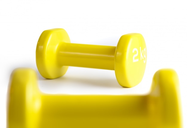 Due dumbbells gialli isolati su fondo bianco con il percorso di ritaglio