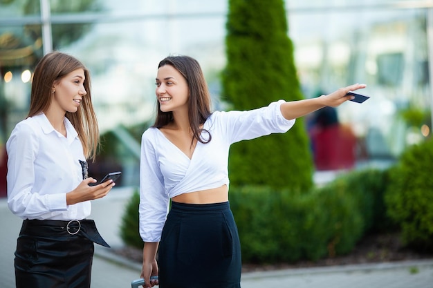 Due eleganti viaggiatori donne che camminano con i loro bagagli in aeroporto