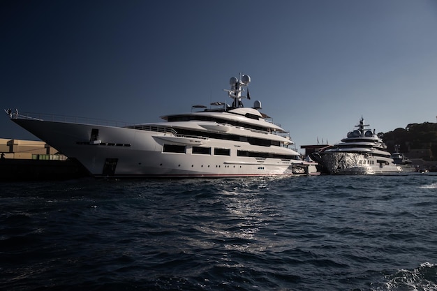 Due enormi yacht nel porto di monaco al tramonto bordo lucido della barca a motore il corrimano cromato...