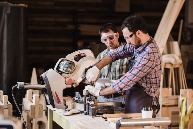 Due falegnami che tagliano la plancia di legno con una sega circolare