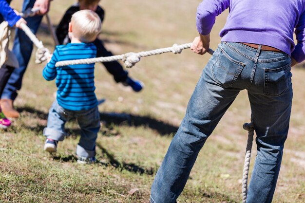 Due famiglie che giocano a tirare la corda vintage nel parco.