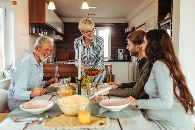 Due famiglie generazionali che pranzano insieme a casa