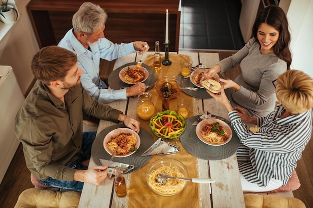 Due famiglie generazionali che si godono il pranzo insieme a casa