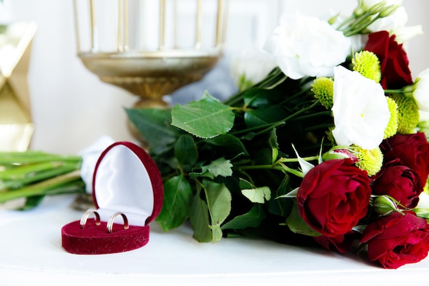 Due fedi nuziali in oro bianco e rosso con bouquet da sposa con rose rosse