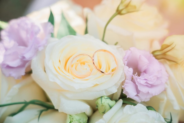 Due fedi nuziali su un bouquet da sposa sotto i raggi del sole Primo piano