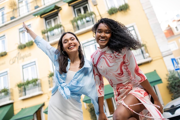 Due felici amiche multietniche che ridono e si divertono mentre posano all'aperto