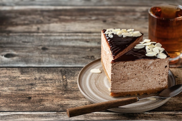 Due fette di cheesecake al cioccolato con petali di mandorla con una tazza di tè su fondo in legno Copia spazio