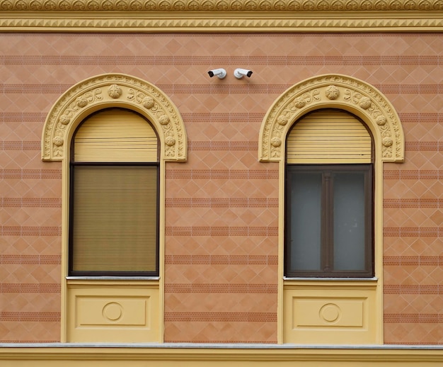 Due finestre con persiane aperte e chiuse sull'edificio giallo ristrutturato