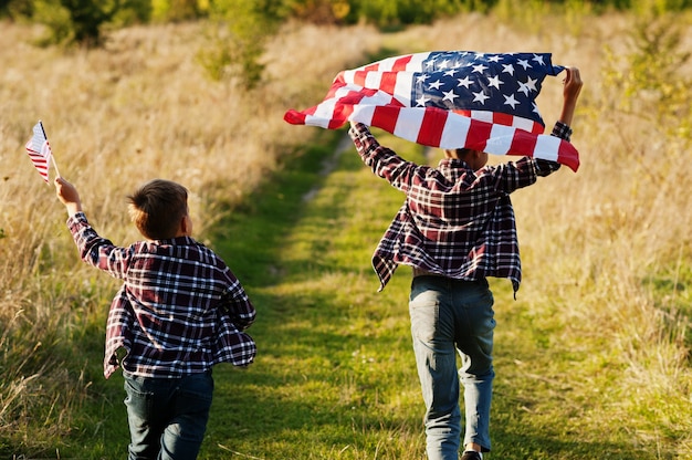 Due fratelli che corrono con la bandiera degli Stati Uniti. Vacanze americane. Orgogliosi di essere figli di campagna.