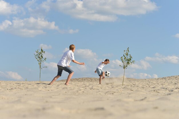 Due fratelli che giocano a calcio sulla spiaggia in un giorno d'estate