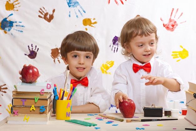 Due fratelli di 7 e 4 anni vestiti con magliette bianche con fiocchi rossi stanno giocando insieme.
