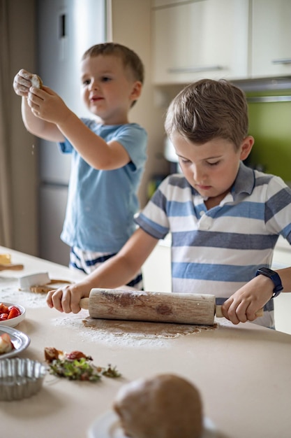 Due fratelli divertenti che cucinano dolci estivi fatti in casa preparano l'impasto e affettano gli ingredienti