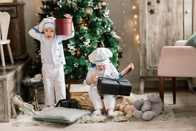 Due fratelli divertenti felici cuociono i biscotti di natale vicino all'albero di natale.