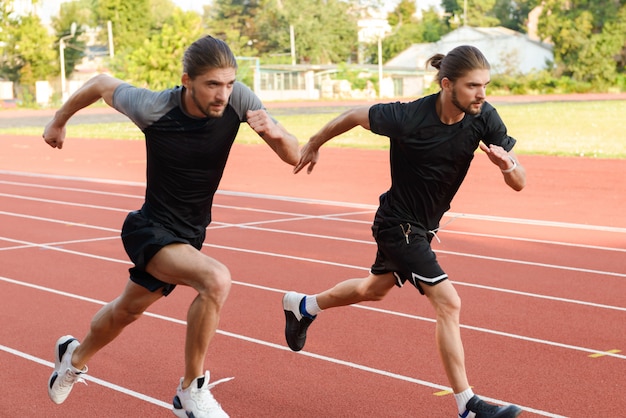 Due fratelli gemelli sportivi che corrono allo stadio all'aperto.