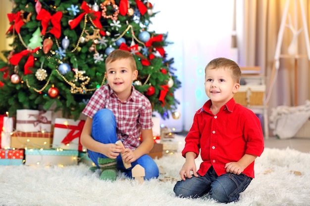 Due fratellini carini che giocano con giocattoli di legno sull'albero di Natale