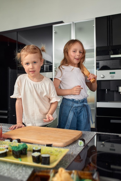 Due fratellini che si divertono e mangiano in cucina a casa con cibo giapponese