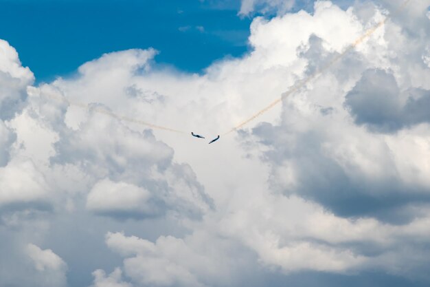 Due getti blu stanno volando l'uno verso l'altro rilasciando un flusso di fumo nel cielo blu con nuvole