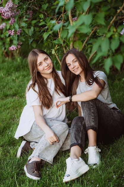 Due giovani adolescenti felici stanno riposando nel parco sull'erba verde. Amicizia femminile. Messa a fuoco selettiva morbida.