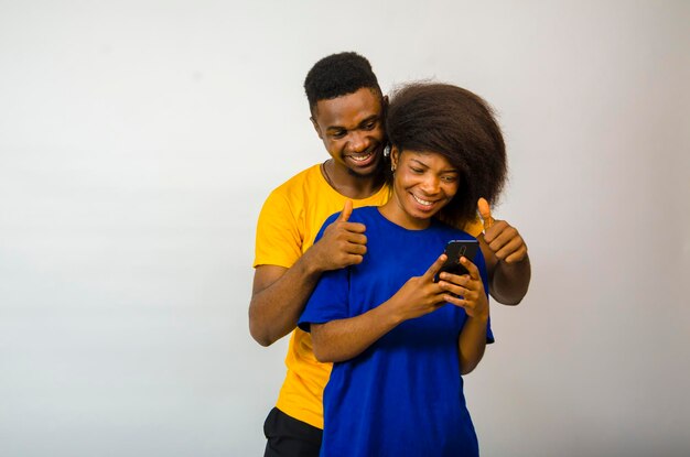 Due giovani africani carini isolati su sfondo bianco che si sentono sovraeccitati per aver visto sul cellulare