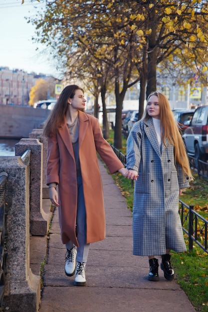 Due giovani alla moda bella donna alla moda in cappotto che cammina sulla strada