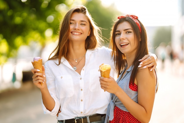 Due giovani amiche divertirsi e mangiare il gelato.