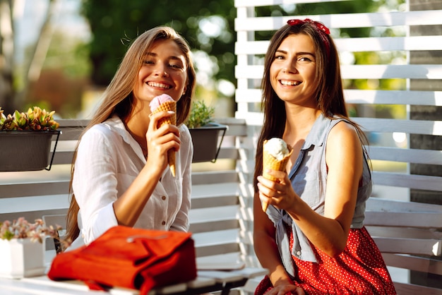 Due giovani amiche divertirsi e mangiare il gelato.