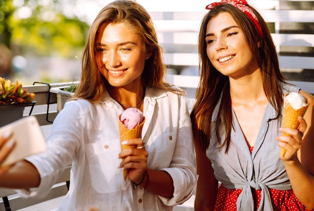 Due giovani amiche divertirsi e mangiare il gelato.