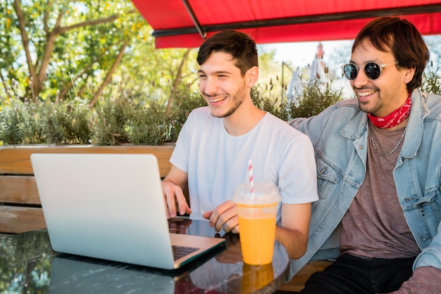 Due giovani amici che per mezzo del computer portatile alla caffetteria.