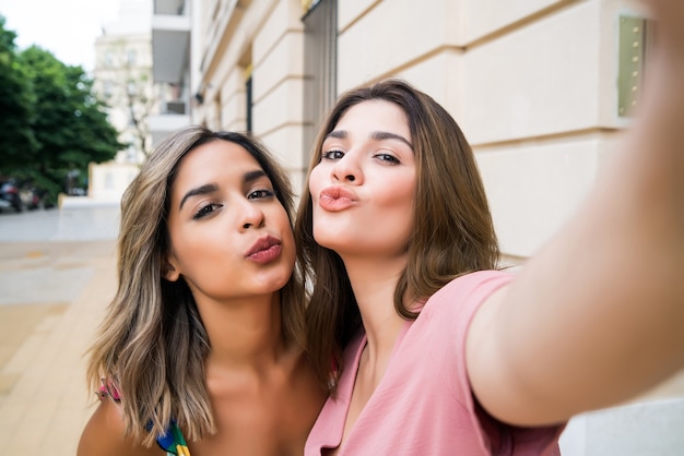 Due giovani amici che trascorrono del tempo insieme e fanno un selfie stando all'aperto. Concetto urbano.