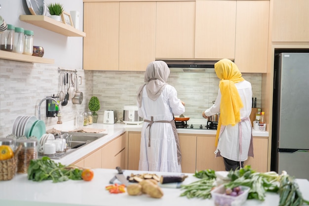 Due giovani attraenti donna musulmana che preparano la cena iftar insieme. Ramadan ed eid mubarak cucinano in cucina