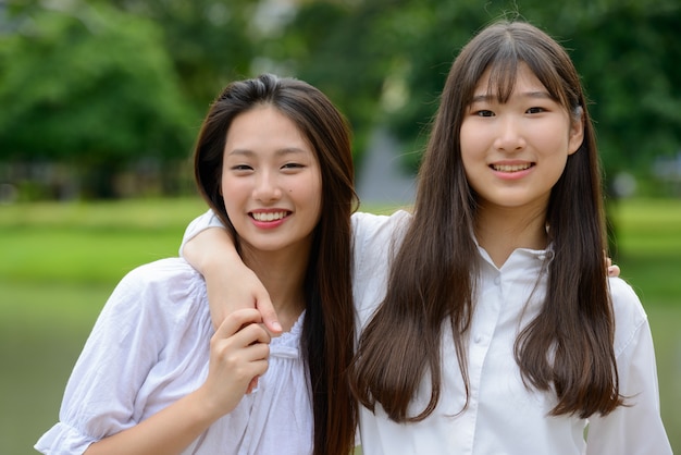 Due giovani belle donne adolescenti asiatiche felici che legano insieme al parco