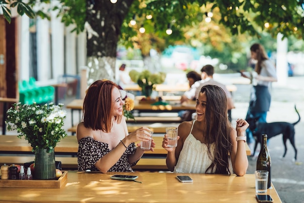 Due giovani belle donne amiche che parlano in un caffè all'aperto