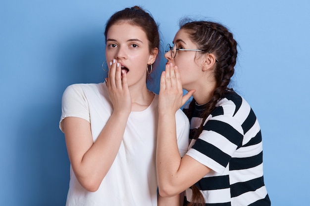 Due giovani belle ragazze dai capelli scuri con espressioni stupite