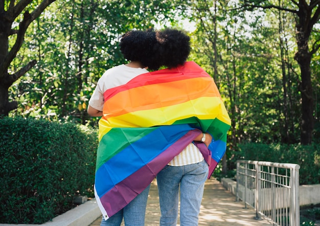 Due giovani belle ragazze sorridenti con bandiera LGBT in giardino