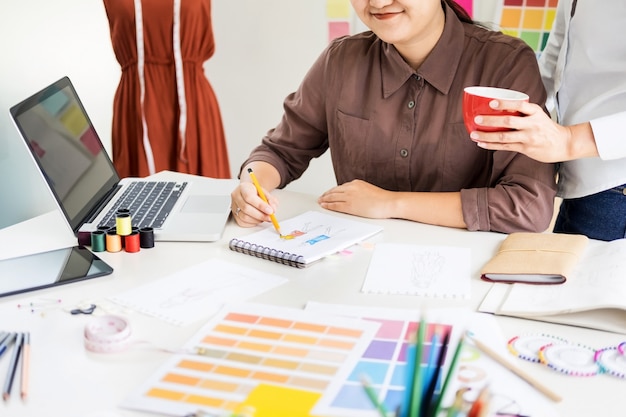 due giovani che lavorano come designer di moda e sketch disegnano e ottengono consigli di tessuto ad un tailor personalizzato.