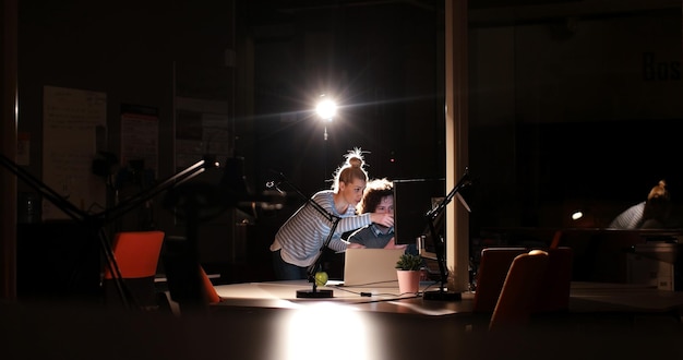 Due giovani designer stanno lavorando a un nuovo progetto nell'ufficio notturno utilizzando la tecnologia moderna