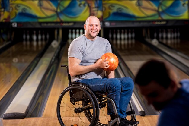 Due giovani disabili in sedia a rotelle che giocano a bowling nel club